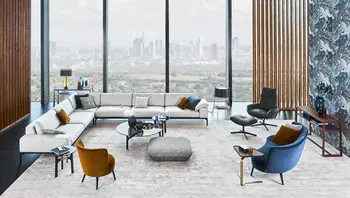 Modernes Wohnzimmer mit hellem Sofasystem von Bielefelder Werkstätten, Design-Sesseln, Beistelltischen und Accessoires – stilvolles Interieur mit Skyline-Blick, erhältlich bei himmlisch wohnen.